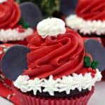 Make this Christmas a Disney Christmas. These adorable Mickey Mouse Santa Cupcakes are the perfect holiday Disney snack to celebrate Christmas. This Disney dessert is so easy and festive. Add a cute Mickey Santa hat to these decorated Christmas cupcakes. #disneysnack #christmascupake #disneyfood