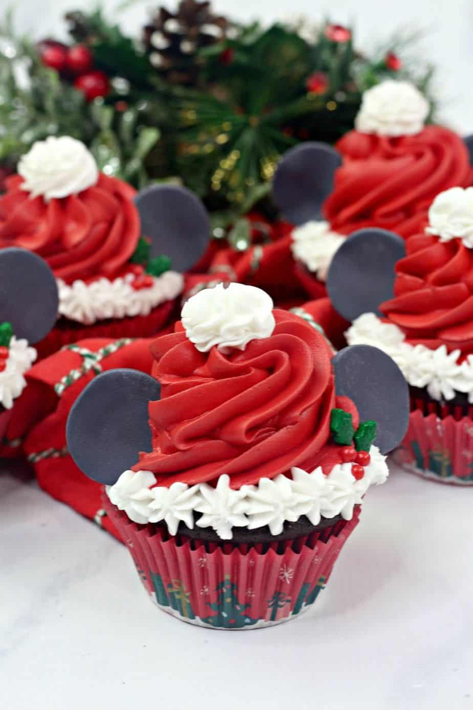 Make this Christmas a Disney Christmas. These adorable Mickey Mouse Santa Cupcakes are the perfect holiday Disney snack to celebrate Christmas. This Disney dessert is so easy and festive. Add a cute Mickey Santa hat to these decorated Christmas cupcakes. #disneysnack #christmascupake #disneyfood