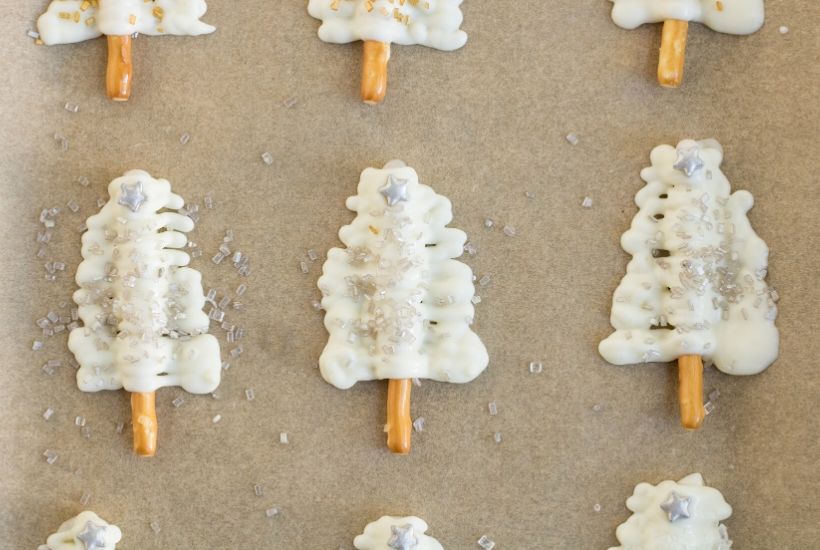 Satisfy your yuletide sweet tooth with these elegant Christmas Tree Cupcakes. This easy Christmas dessert recipe is perfect for your holiday spread. White Chocolate and pretzel sticks make the pretty glittering Christmas tree topper. #christmascupcake #cupcakerecipe #dessert