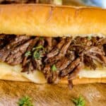 These flavorful Easy Crock Pot French Dip Sandwiches are a family favorite. Top them with provolone cheese and serve with a side of au jus. This Slow Cooker French Dip Sandwich recipe is perfect for a weeknight meal or to serve at a game day party or casual get together. This is an easy sandwich recipe that everyone will enjoy. #frenchdip #slowcookerrecipe #crockpotrecipe #slowcookerfrenchdip