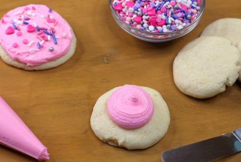 These soft and buttery Valentine Lofthouse Sugar Cookies are the perfect sweet treat. These sour cream cookies are topped with sweet frosting and sprinkles. This is an easy sugar cookie recipe that requires no rolling. You can make them for any season or holiday by just changing the color of the frosting. #sugarcookies #lofthousecookies #valentinesdayrecipe #partyidea