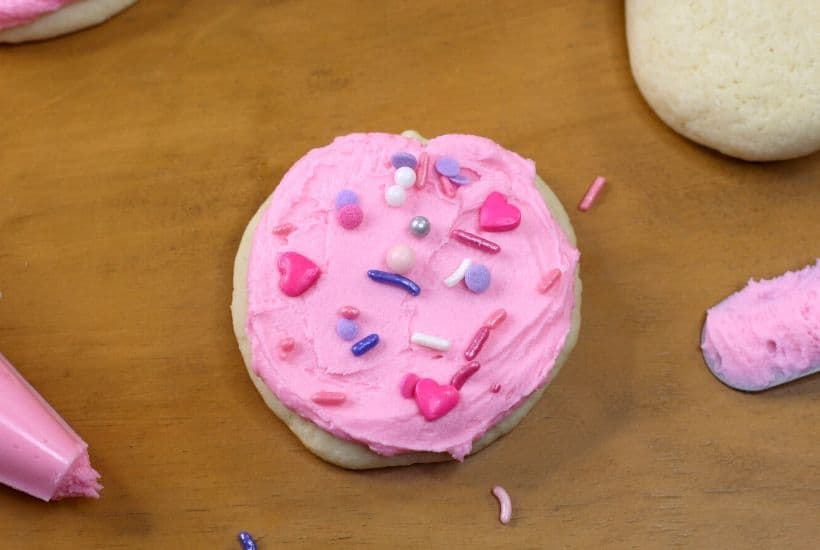 These soft and buttery Valentine Lofthouse Sugar Cookies are the perfect sweet treat. These sour cream cookies are topped with sweet frosting and sprinkles. This is an easy sugar cookie recipe that requires no rolling. You can make them for any season or holiday by just changing the color of the frosting. #sugarcookies #lofthousecookies #valentinesdayrecipe #partyidea