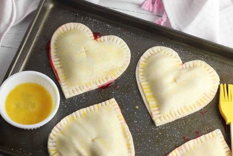These Heart-Shaped Cherry Hand Pies are the perfect snack. Each hand pie is filled with sweet cherry pie filling sandwiched in between a flaky pie crust, then baked to perfection.