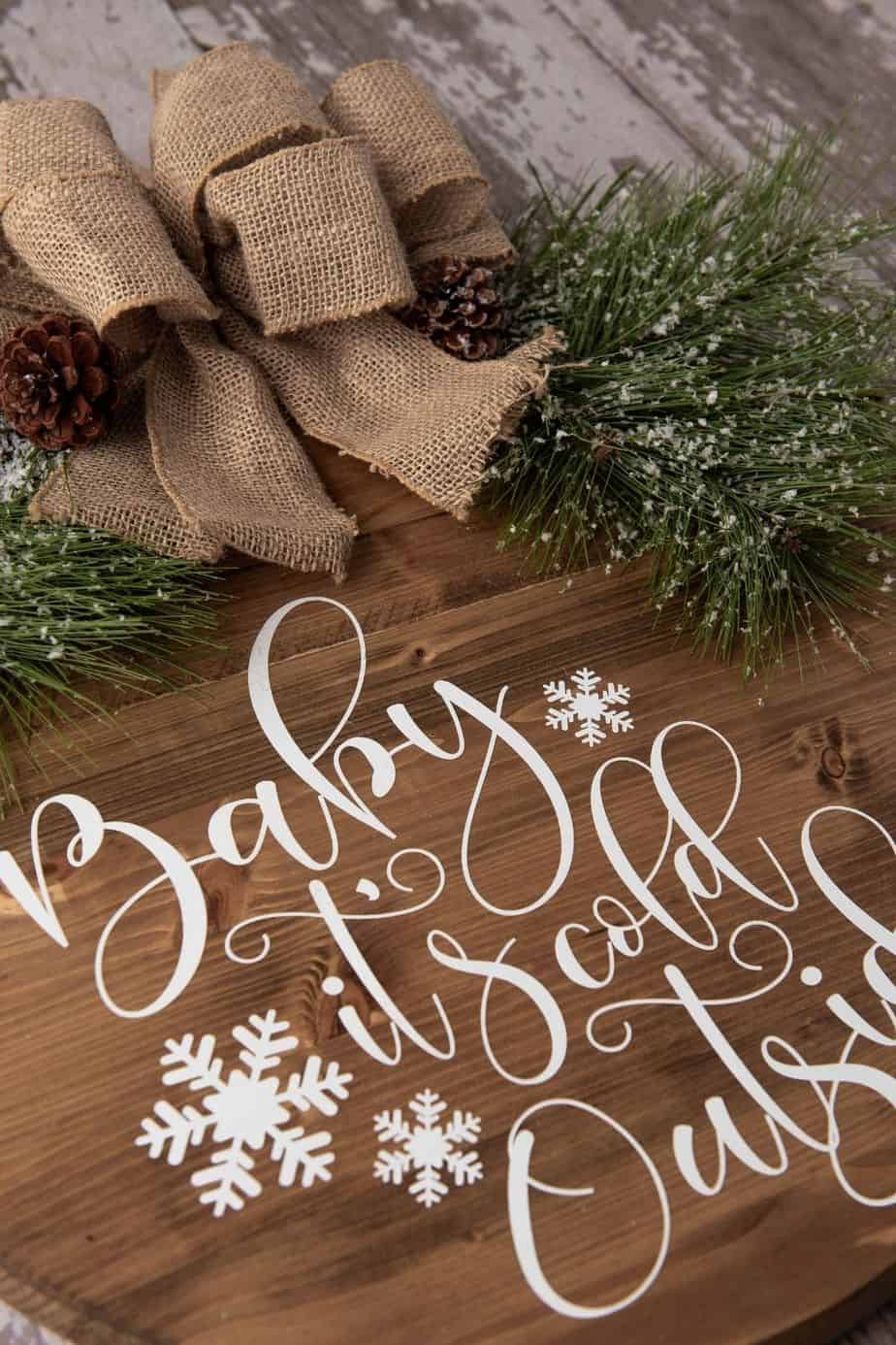 Make a decorative piece to hang in your home with this easy winter craft idea. Make a DIY Farmhouse Winter Sign that will add a special touch to any room in the home. This Christmas Cricut craft is a great project to make. It can be left up long after Christmas is over. Be sure to download the FREE SVG file - Baby It's Cold Outside too. Hang this sign on your entryway door or on a wall in your home.