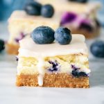 Ditch the traditional cheesecake that you have to eat with a fork and try this simple recipe for Blueberry Cheesecake Bars. These moist and delicious bars are full of sweet flavor and are perfect for a grab and go dessert. This easy blueberry dessert is a perfect dessert recipe for a party or potluck. Make this delicious bar recipe while blueberries are in peak season during the summer months.