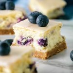 Ditch the traditional cheesecake that you have to eat with a fork and try this simple recipe for Blueberry Cheesecake Bars. These moist and delicious bars are full of sweet flavor and are perfect for a grab and go dessert. This easy blueberry dessert is a perfect dessert recipe for a party or potluck. Make this delicious bar recipe while blueberries are in peak season during the summer months.