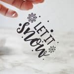 Who says you need the most expensive ornaments to make your Christmas tree look amazing? Learn how to easily create the most beautiful Let It Snow Ornament to hang on the tree or give as a gift. This DIY Ornament is an easy holiday Cricut Craft Idea. It is a great homemade Christmas gift craft idea.